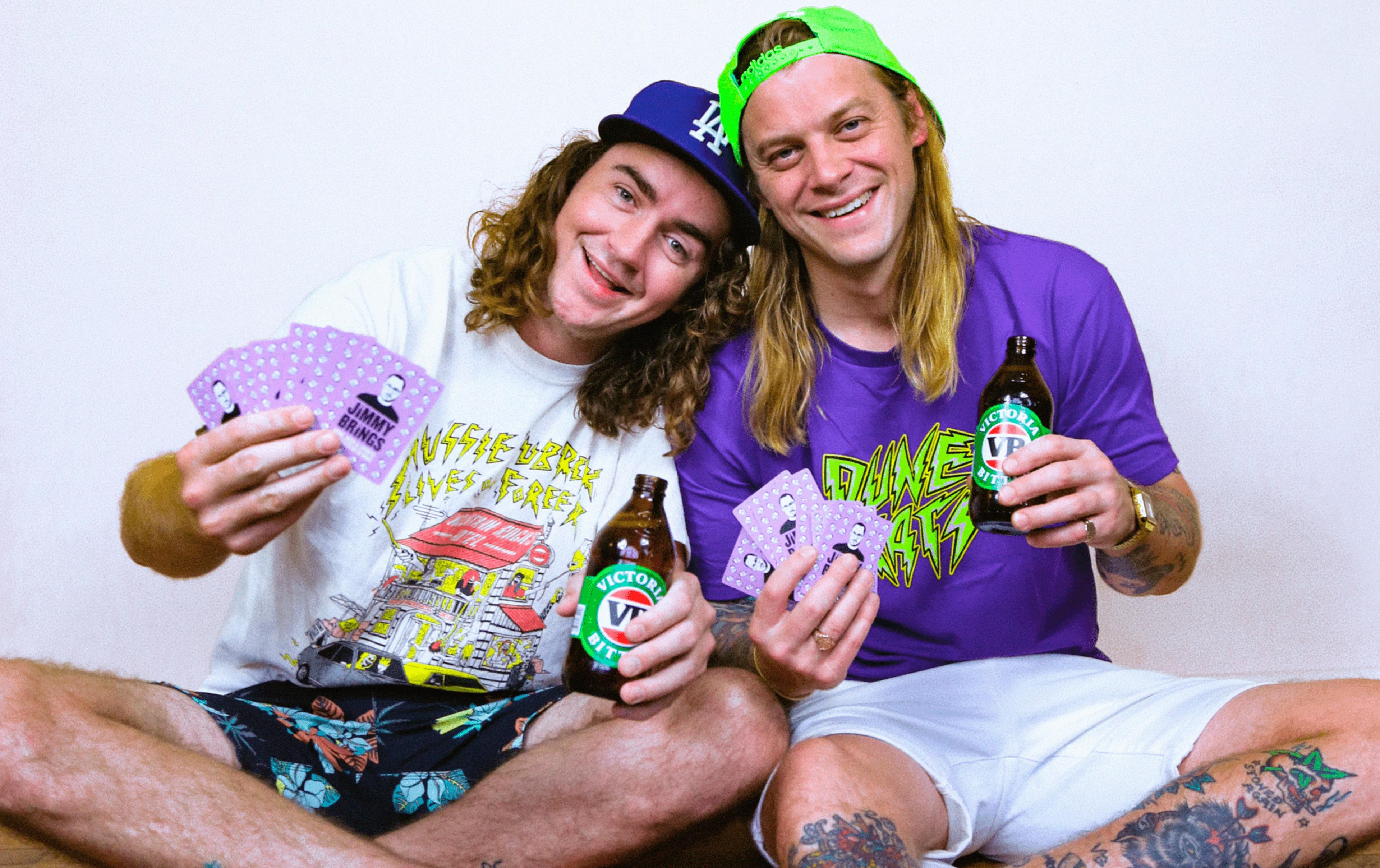 The duo from 'The Dune Rats' in t shirts holding VB's and purple cards in their hands. 