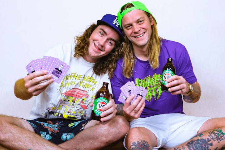 The duo from 'The Dune Rats' in t shirts holding VB's and purple cards in their hands. 