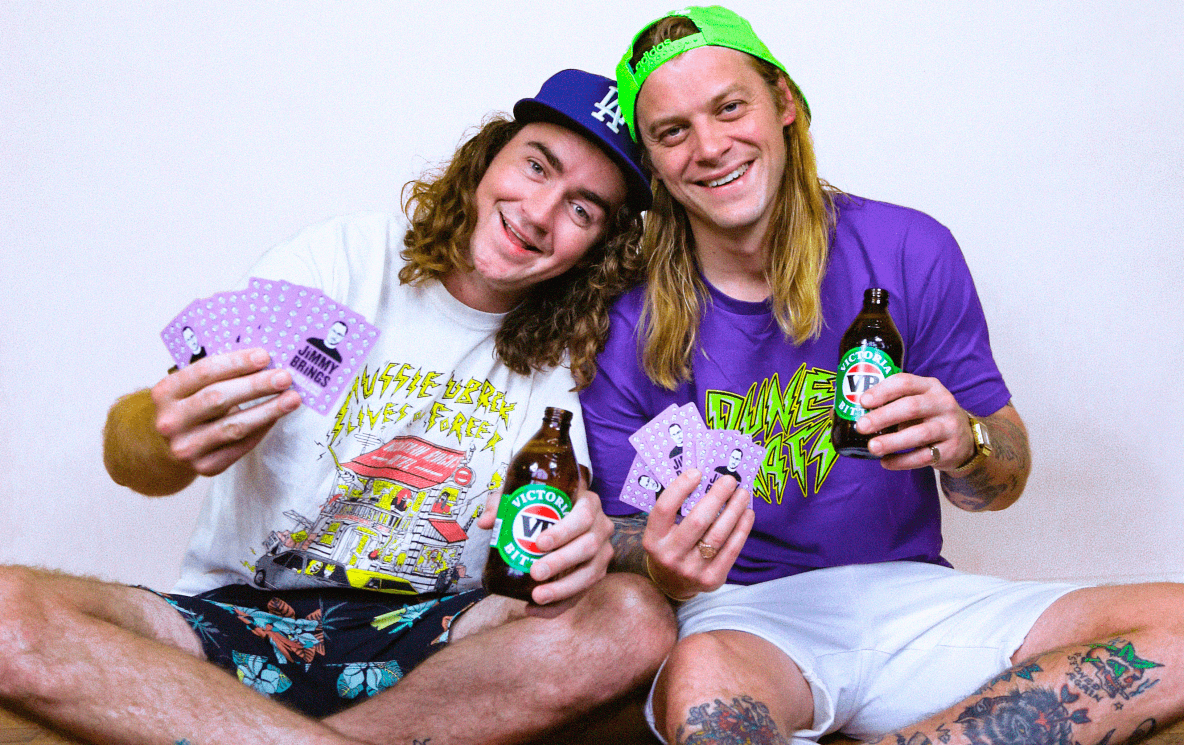 The duo from 'The Dune Rats' in t shirts holding VB's and purple cards in their hands. 