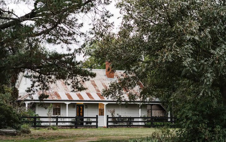 The outside of one of the best romantic getaways in Victoria with white-painted walls and a tin roof.