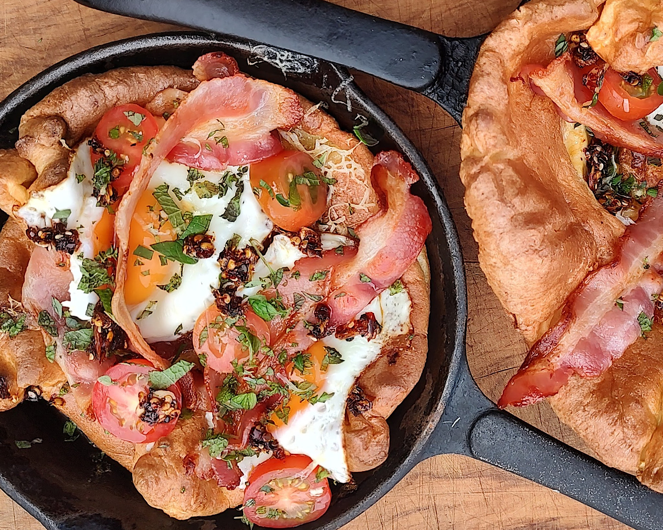 Dutch babies in skillet pans, topped with eggs, bacon, chilli and herbs. 