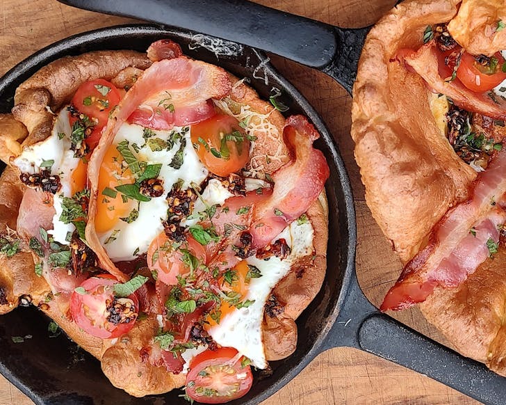 Dutch babies in skillet pans, topped with eggs, bacon, chilli and herbs. 