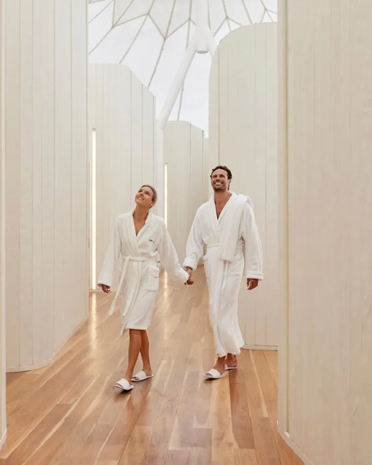 Two people in robes walking around white walled tent