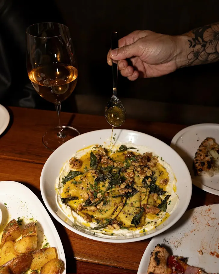 Plate of pasta with wine glasses and olive oil drizzle