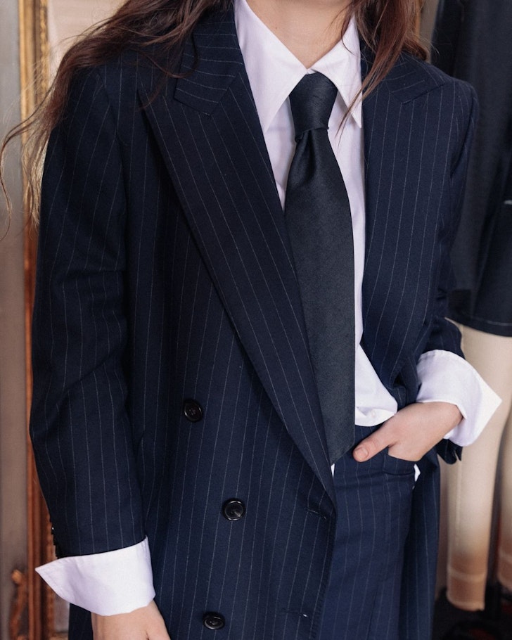 A woman wears a suit and tie from E Nolan one of the best Australian fashion labels