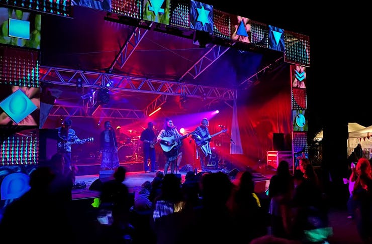 A band plays on stage bathed in purple and red lights at Earth Beat Festival, one of the best things to do in Auckland this weekend. 