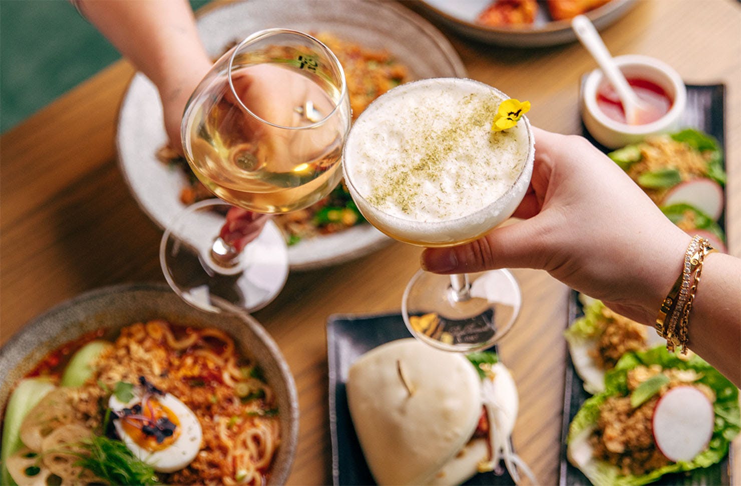 Two people cheers over a fine spread of vegetarian food.
