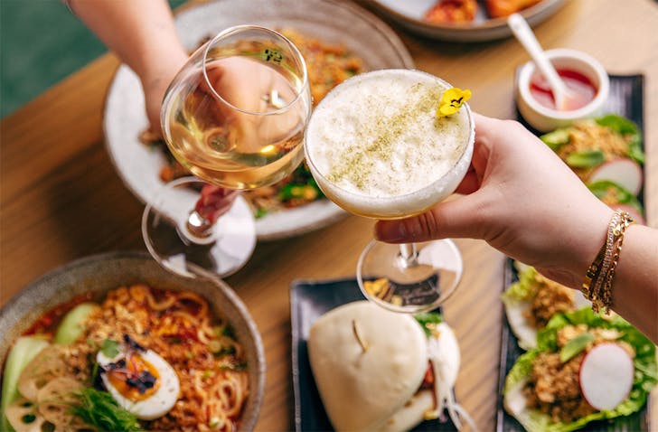 Two people cheers over a fine spread of vegetarian food.
