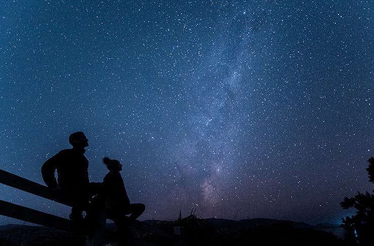 Two people gaze up at the night sky at Eastern Walkway, one of the best stargazing spots  in Wellington.
