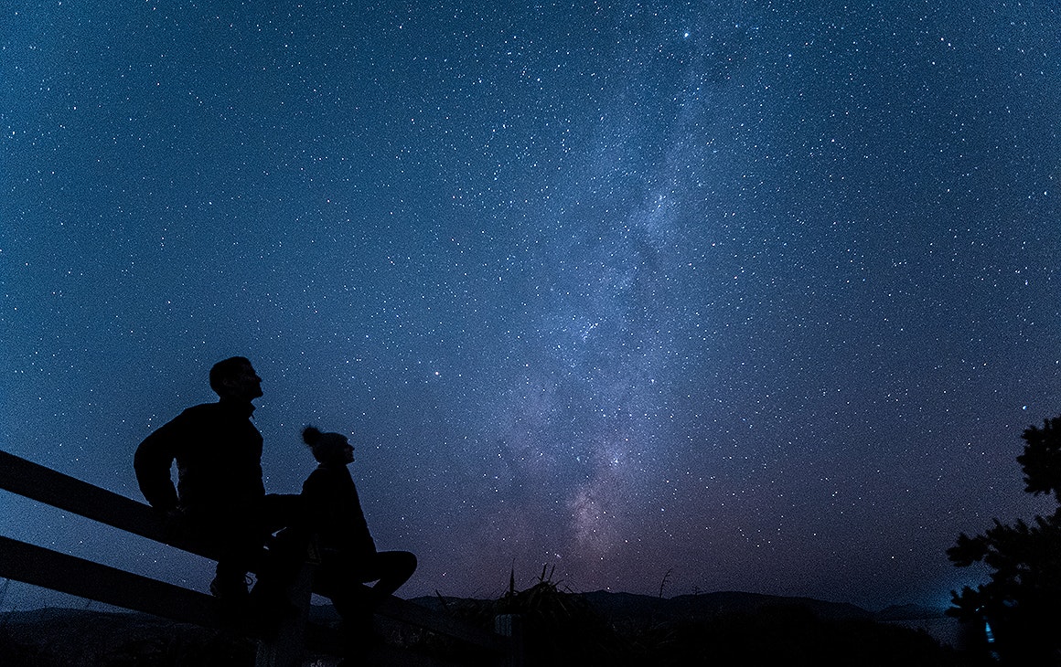 Two people gaze up at the night sky at Eastern Walkway, one of the best stargazing spots  in Wellington.
