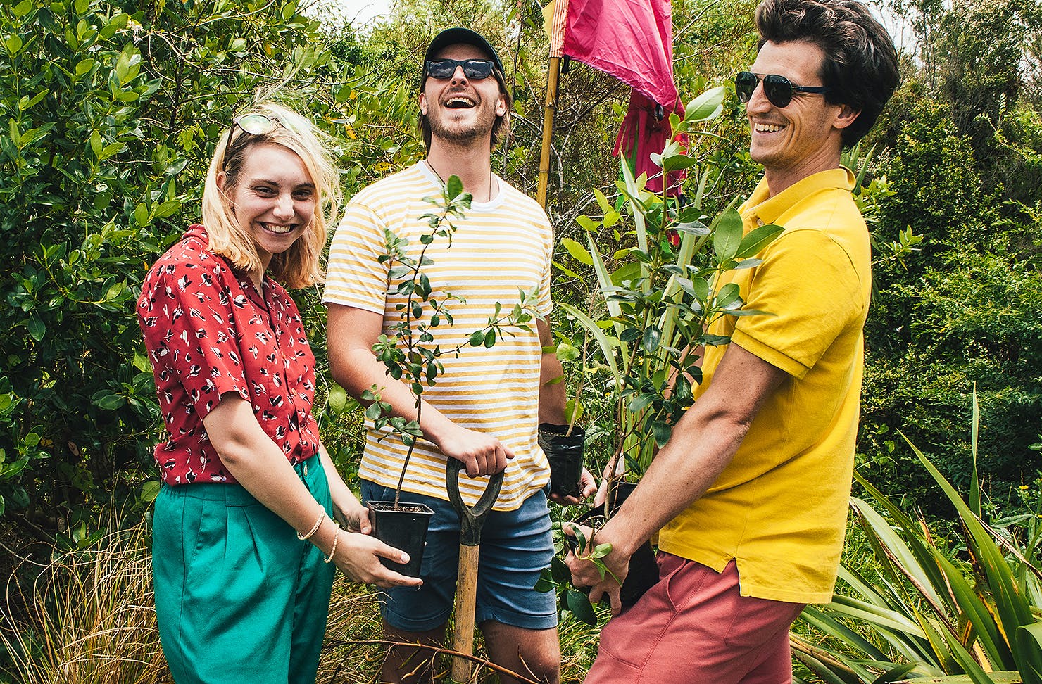 Three people have fun while planting trees.