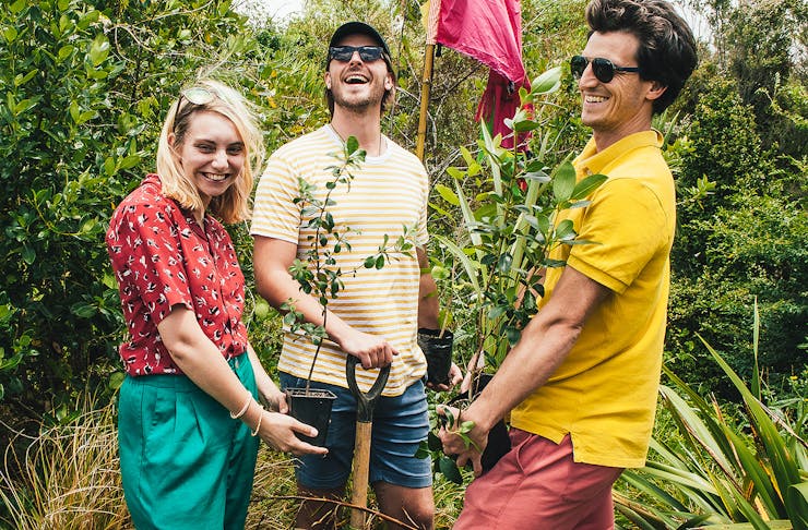 Three people have fun while planting trees.