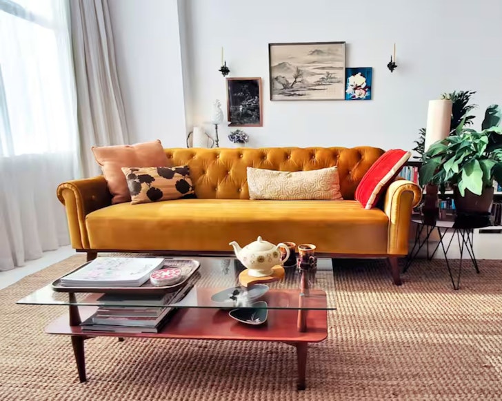 The vibrant yellow couch at Eco Art Deco In The City one of the best Wellington Airbnbs