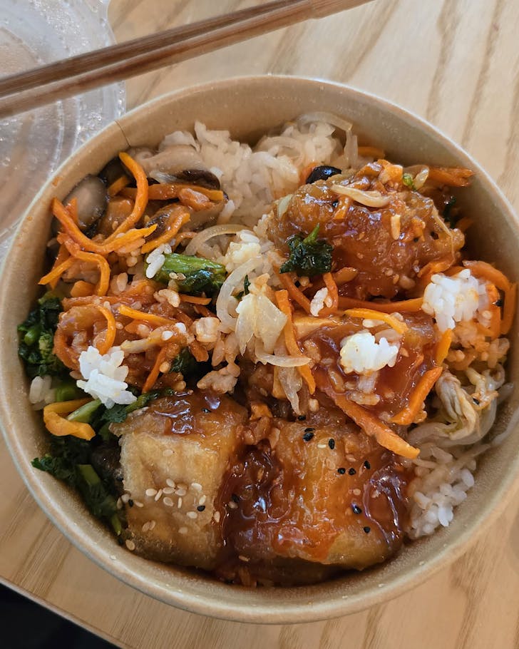 A takeaway bibimbap box and wooden chopsticks.