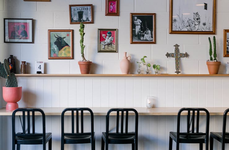 Bar seating underneath a wall of framed prints