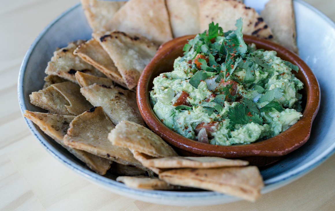 a plate of corn chips and guacamole