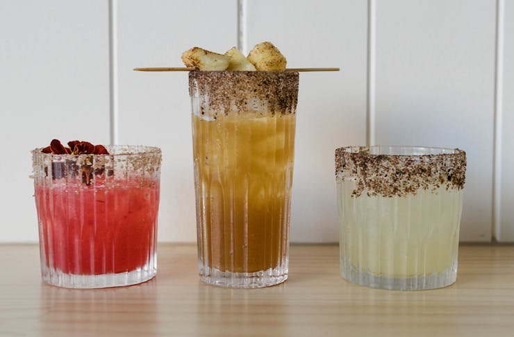 three different cocktails lined up on a bench
