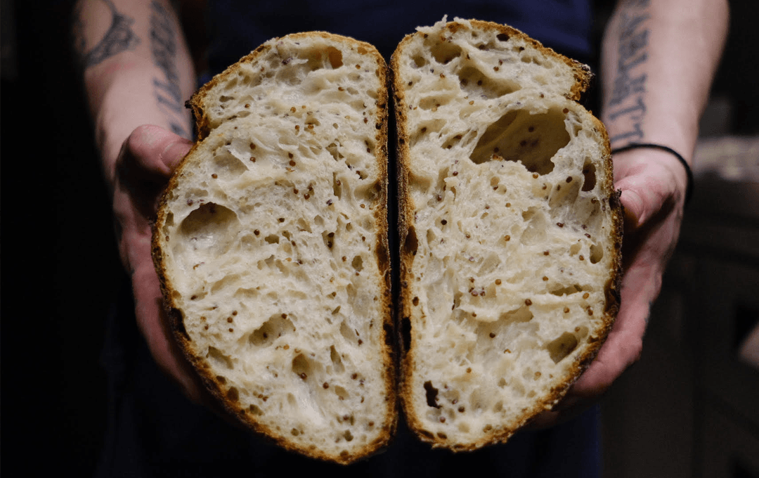 Bread from one of Melbourne's best restaurants being opened up by tattooed hands.