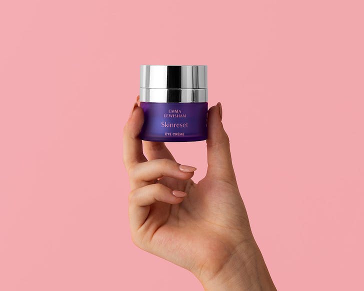 Someone holds the new skin reset eye creme aloft.