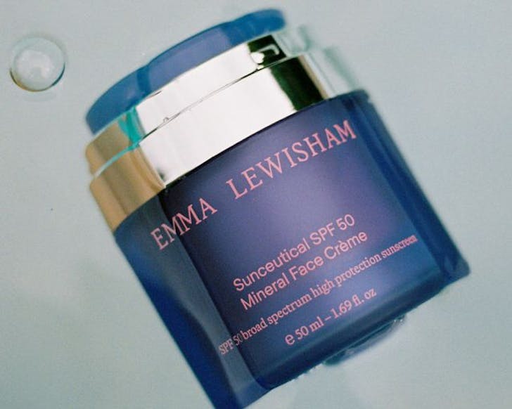 A small dark blue container of Emma Lewisham sunceutical mineral face creme lies in water. 