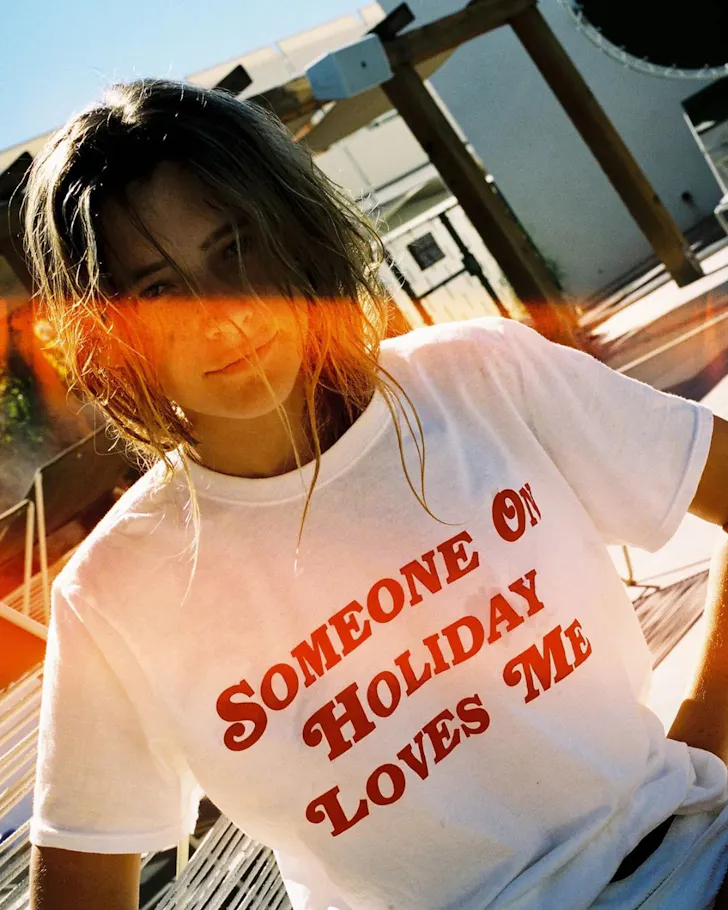 A woman wears a slogan t-shirt from Emma Mulholland On Holiday one of the best Australian fashion labels