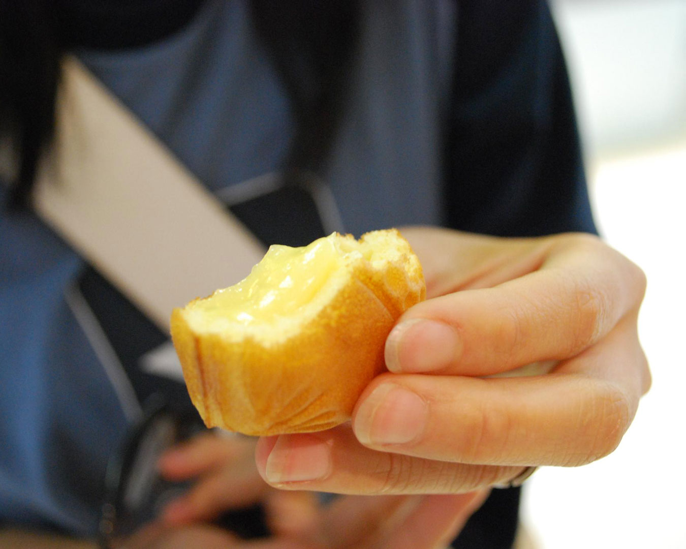 hand holding a half-eaten cream puff