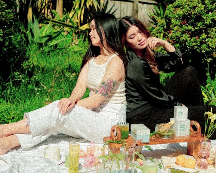 Enna and May sit on a picnic rug surrounded by matcha. 