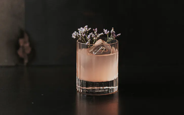 a pink cocktail topped with botanicals