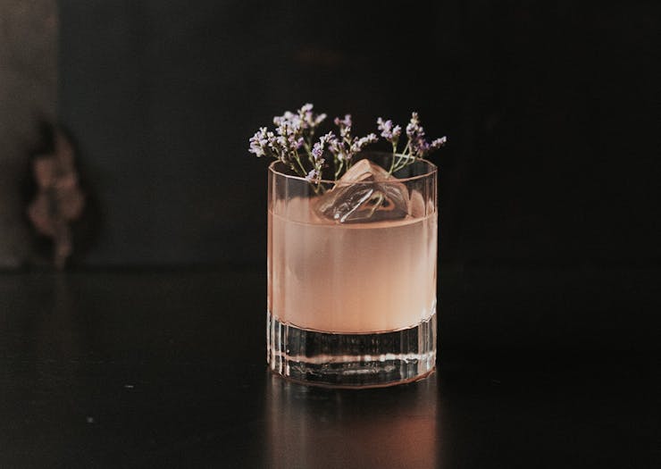 a pink cocktail topped with botanicals