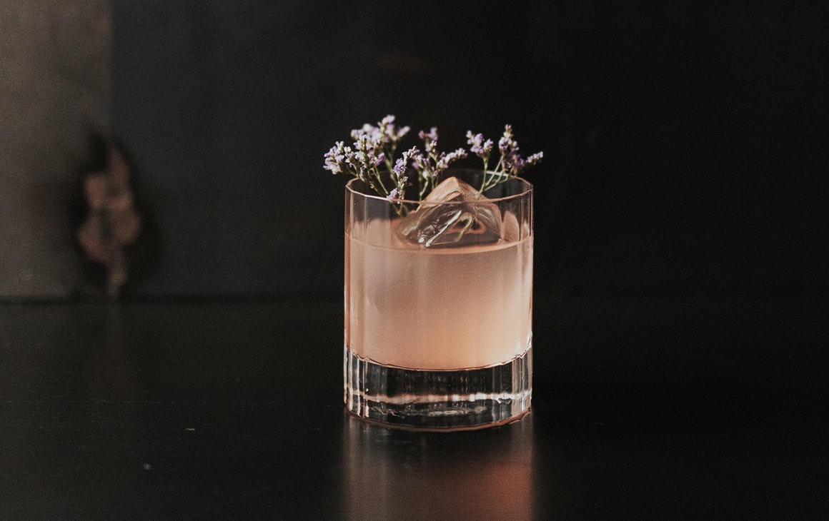 a pink cocktail topped with botanicals