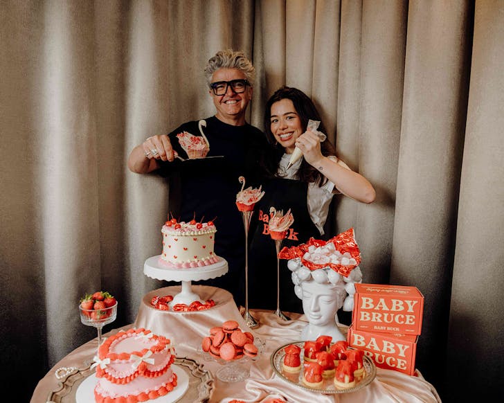 Two chefs pose with the most beautiful table of pink and red Valentine's Day treats.