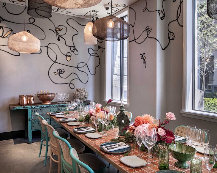 A table with a tiled top and blue and beige chairs in a lounge adorned with upbeat squiggles.