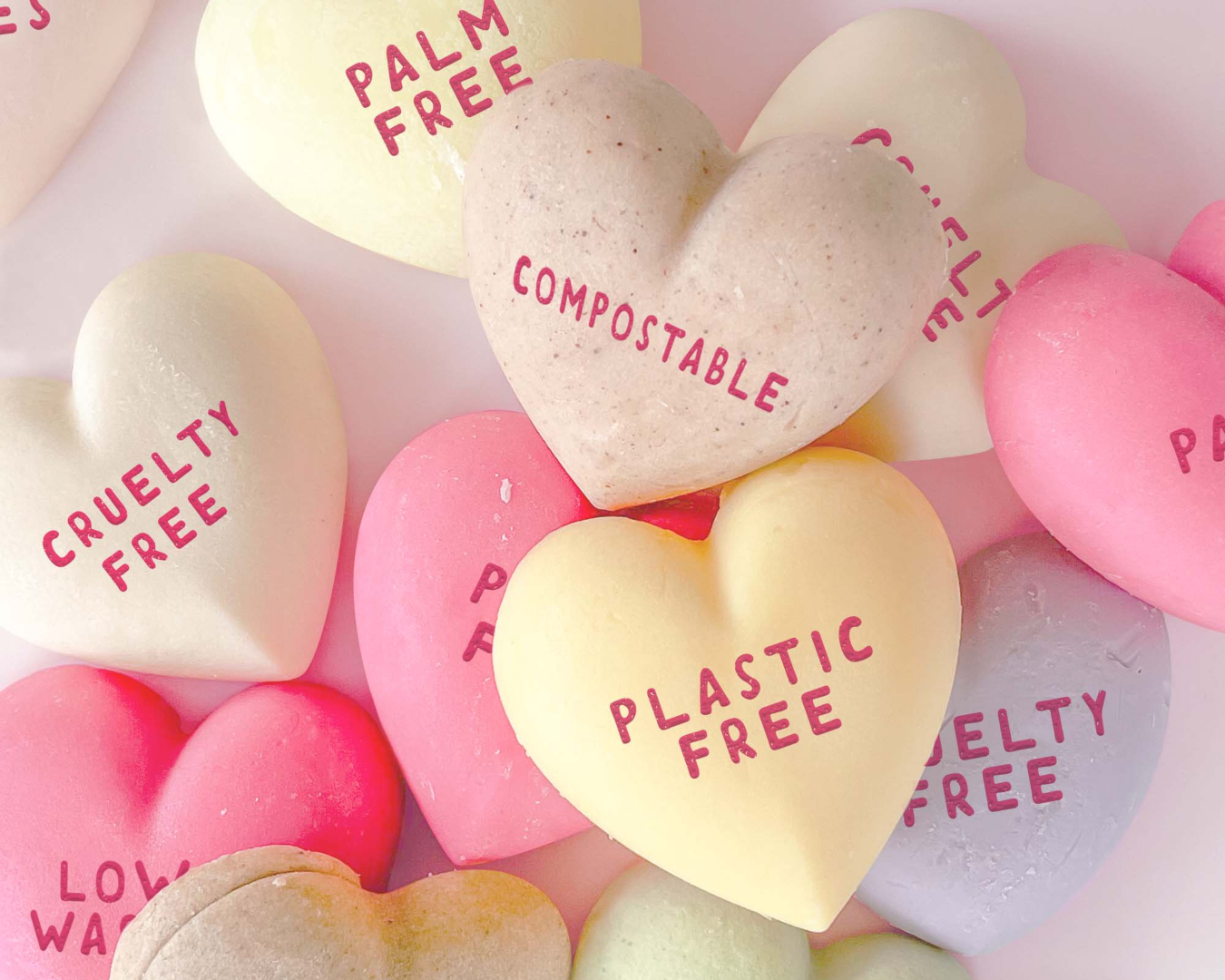 Different coloured hearts of Ethique sampler bars with statements such as 'plastic free', 'compostable' and 'cruelty free' written on each one in pink lettering.