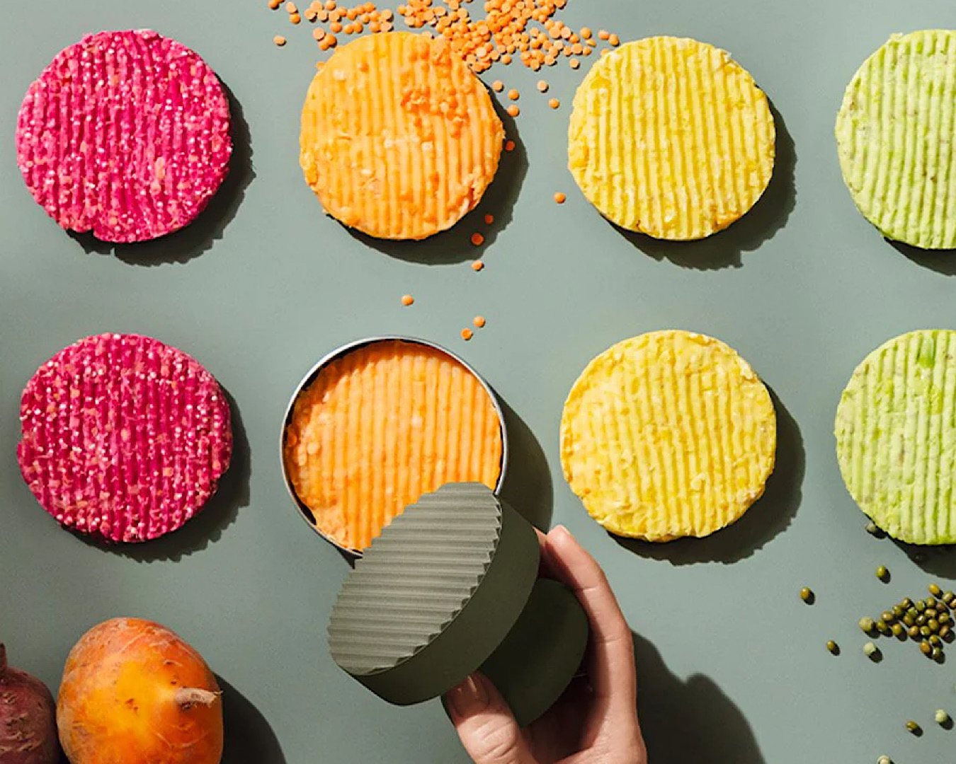 A person uses a chic steel and green stamp-like burger press to create perfectly round burger patties out of different coloured vegetables in celebration of Father’s Day. 