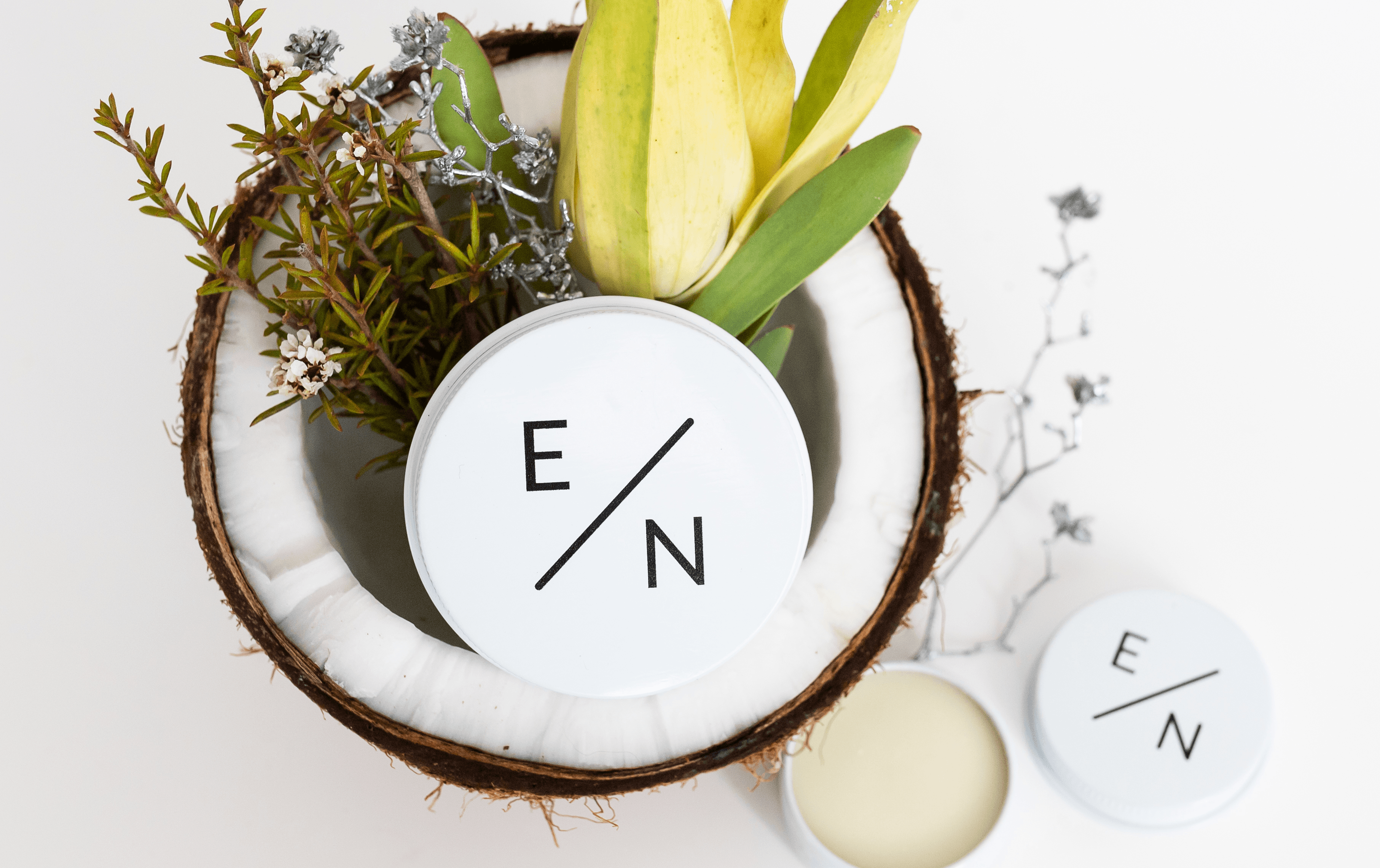 A tin of exposed naturals deodorant on top of a half-cut coconut. 