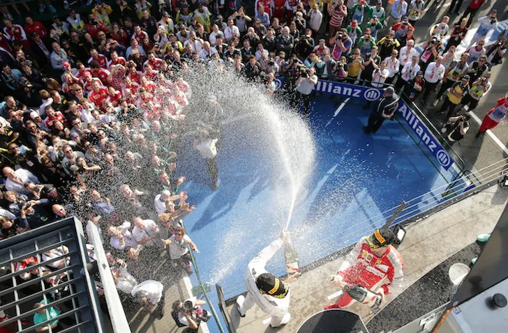 A F1 podium with people spraying champagne. 