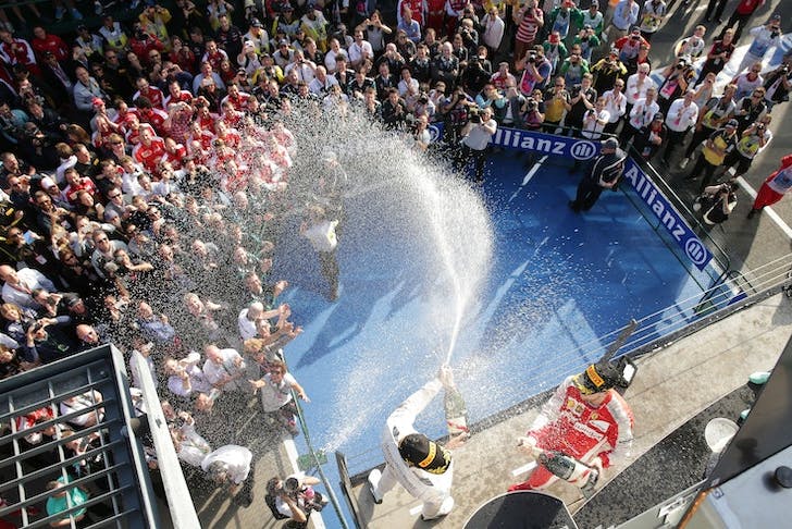 A F1 podium with people spraying champagne. 