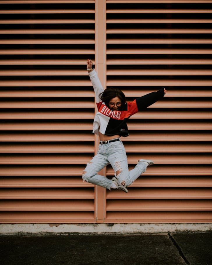 A girl wearing glasses leaps for joy