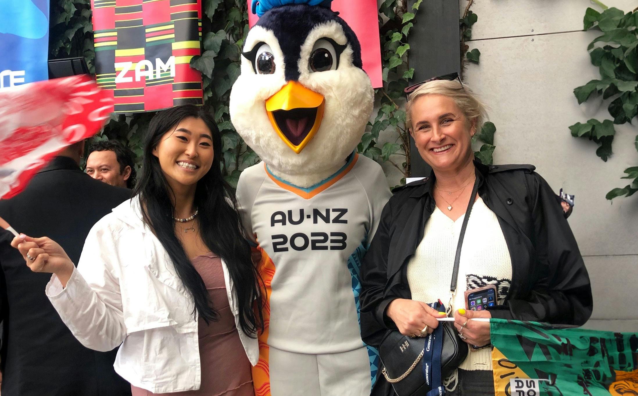 Two woman and the FIFA WWC mascot smile together