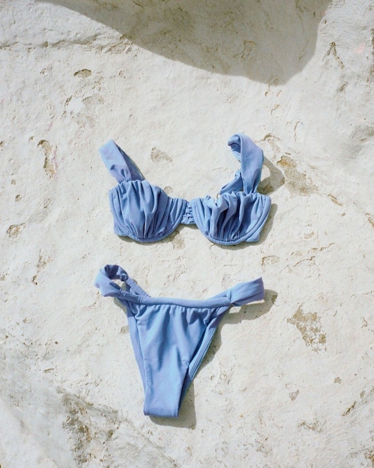 A blue bikini lies on the sand by Faithfull The Brand one of the best Australian swimwear labels