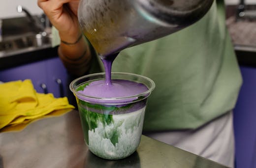 Pouring purple ube cream on top of matcha.