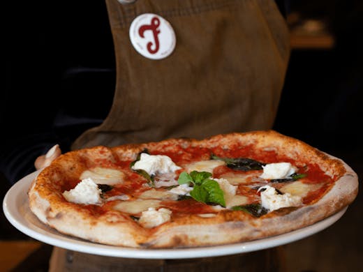 A person holding up a pizza on a plate. 