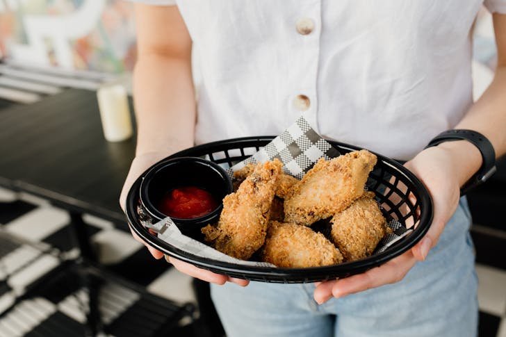 someone holding chicken wings