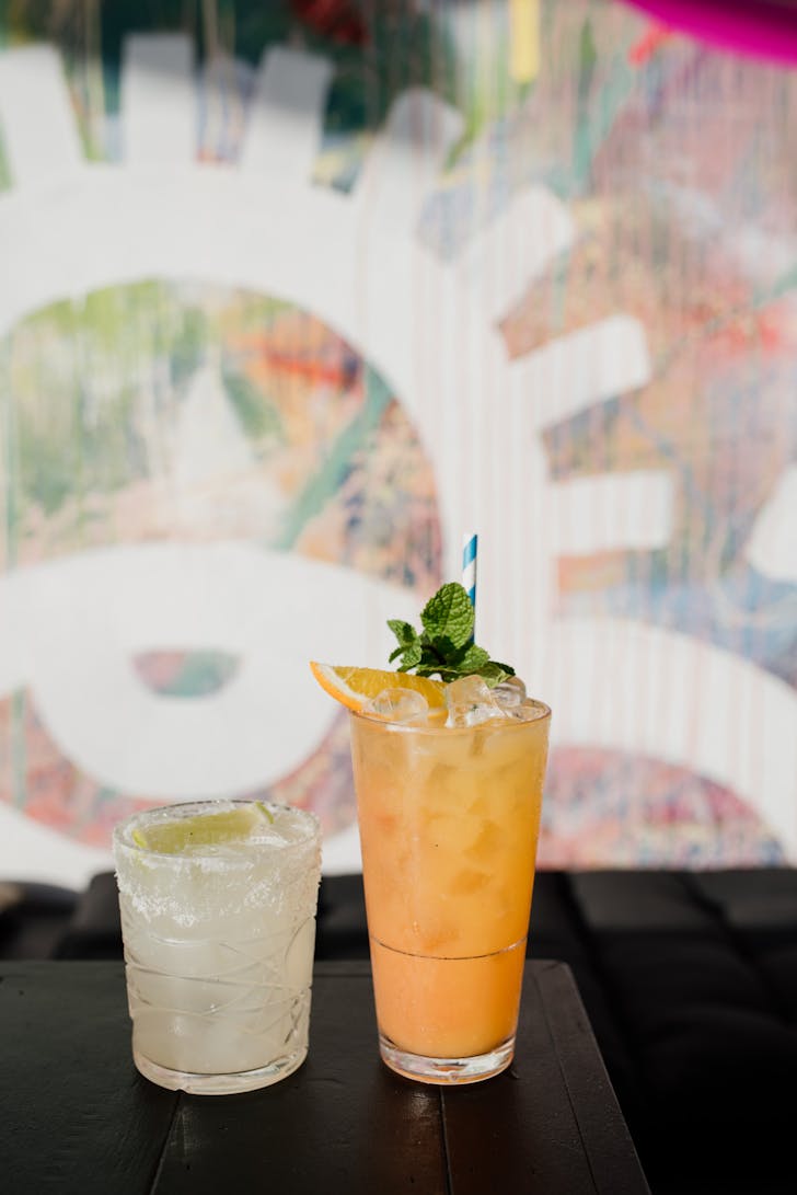 two cocktails against a graffitied wall