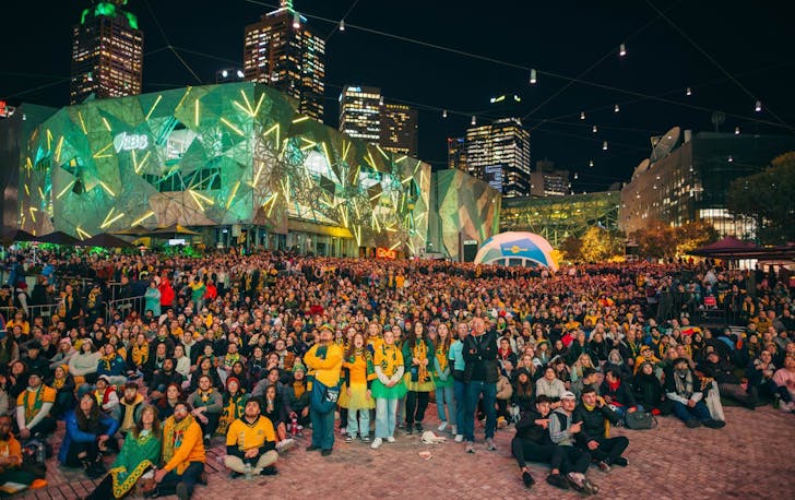 A group of people in green and gold at Federation Square. 