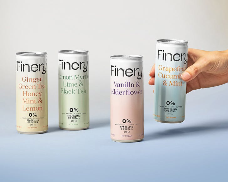 A hand reaches out to grab a Finery 0% cocktail in a can.