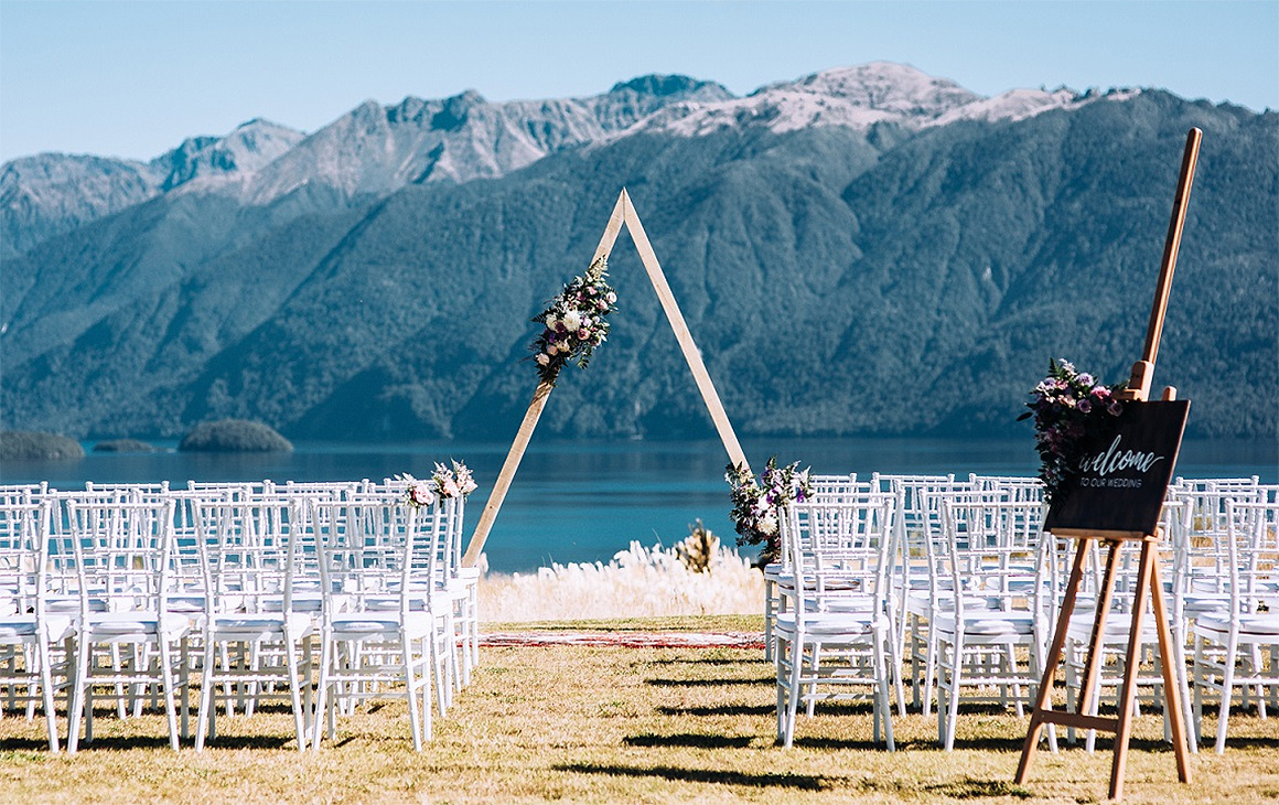 Lines of white chairs and a wedding arch set up at Fiordland Lodge just awaits the bride and groom.