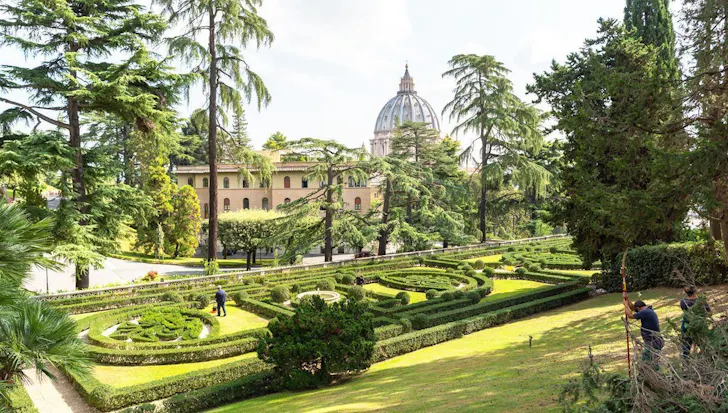 Sprawling gardens with a view of St Peter's Basilica dome at The Vatican in Rome