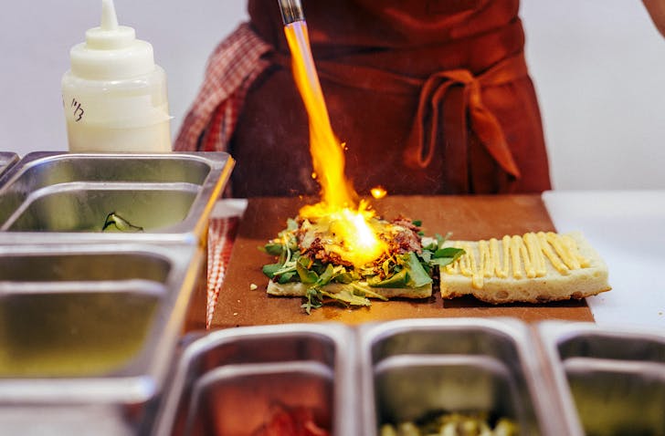 A chef blow torches the cheese on a stacked sando at Fitzroy Deli. 