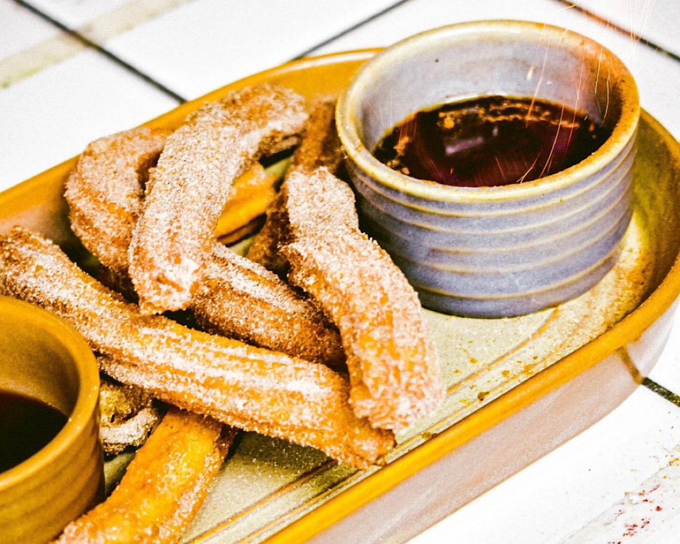 Crispy churros with a flaming rum chocolate dipping sauce at De Nada, one of the best late-night dessert spots in Auckland. 